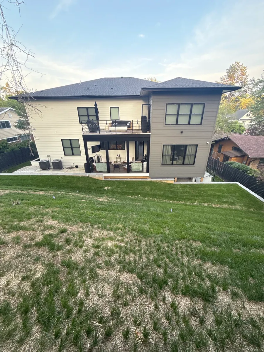 Sloped bare lawn behind a large modern home in McLean Virginia before hardscape construction